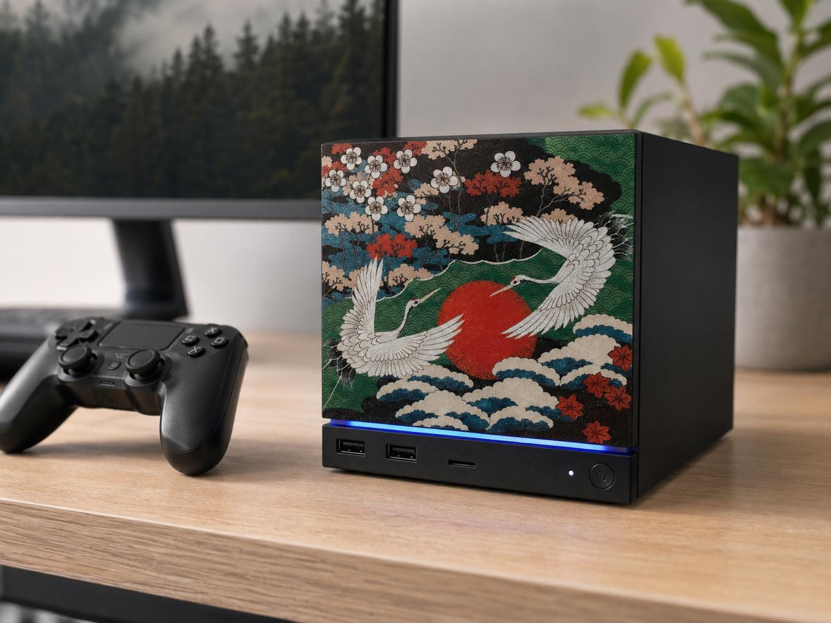 Japanese Crane Steam Machine Faceplate – UV Printed Front Panel | Red Sun & Cherry Blossom Art | Custom Mini PC Cover | Gamer Gift, angled view of the crane faceplate installed on the console on a light wooden desk, with a black game controller beside it and a blurred monitor and plant in the background