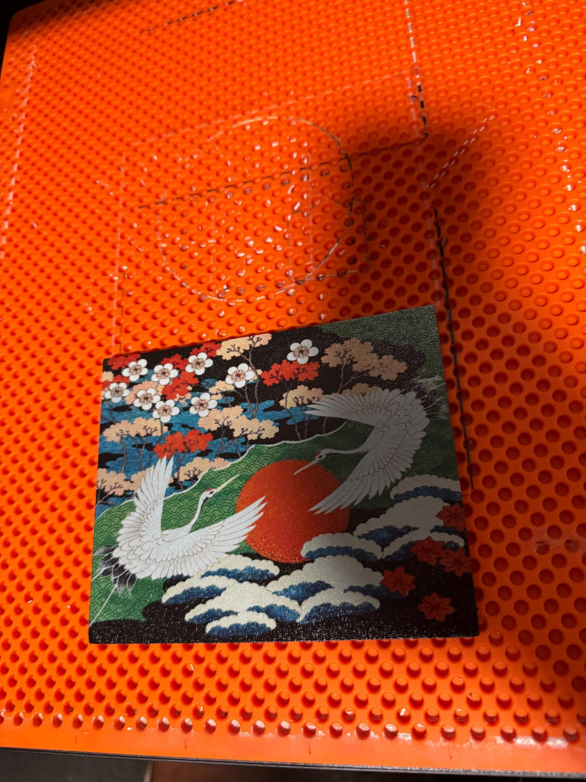 Japanese Crane Steam Machine Faceplate – UV Printed Front Panel | Red Sun & Cherry Blossom Art | Custom Mini PC Cover | Gamer Gift, top-down view of the uninstalled crane faceplate panel with cranes, red sun, and cherry blossoms, on an orange perforated build plate