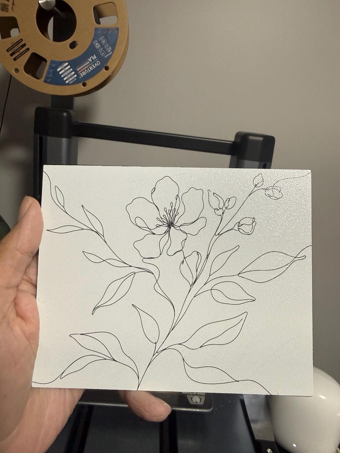 Botanical Line Art Steam Machine Faceplate | Minimalist Plant UV Print Skin held in a hand, showing the line-drawn flower and leaves on the detached panel in front of a 3D printer
