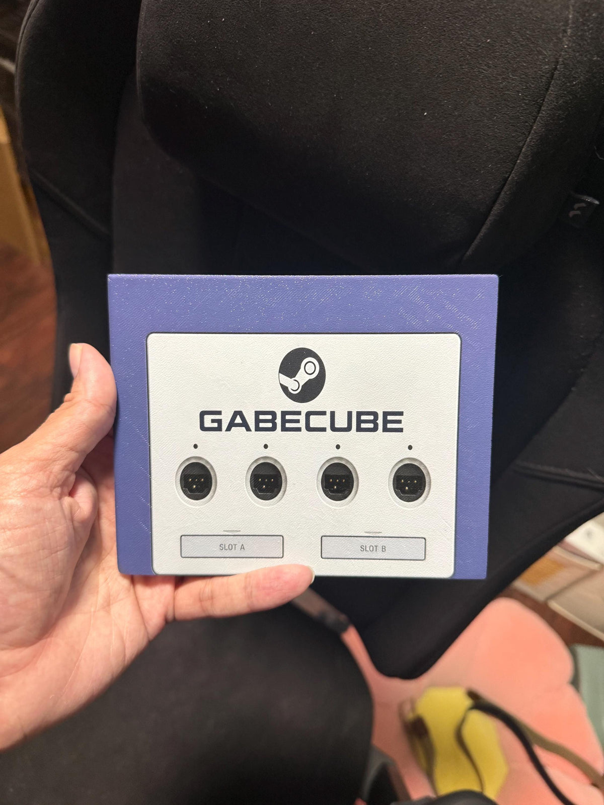 3D Printed GameCube Faceplate – Indigo Purple Steam Machine Controller Panel, hand holding the uninstalled GabeCube faceplate panel showing the Steam logo, four controller ports and slot labels