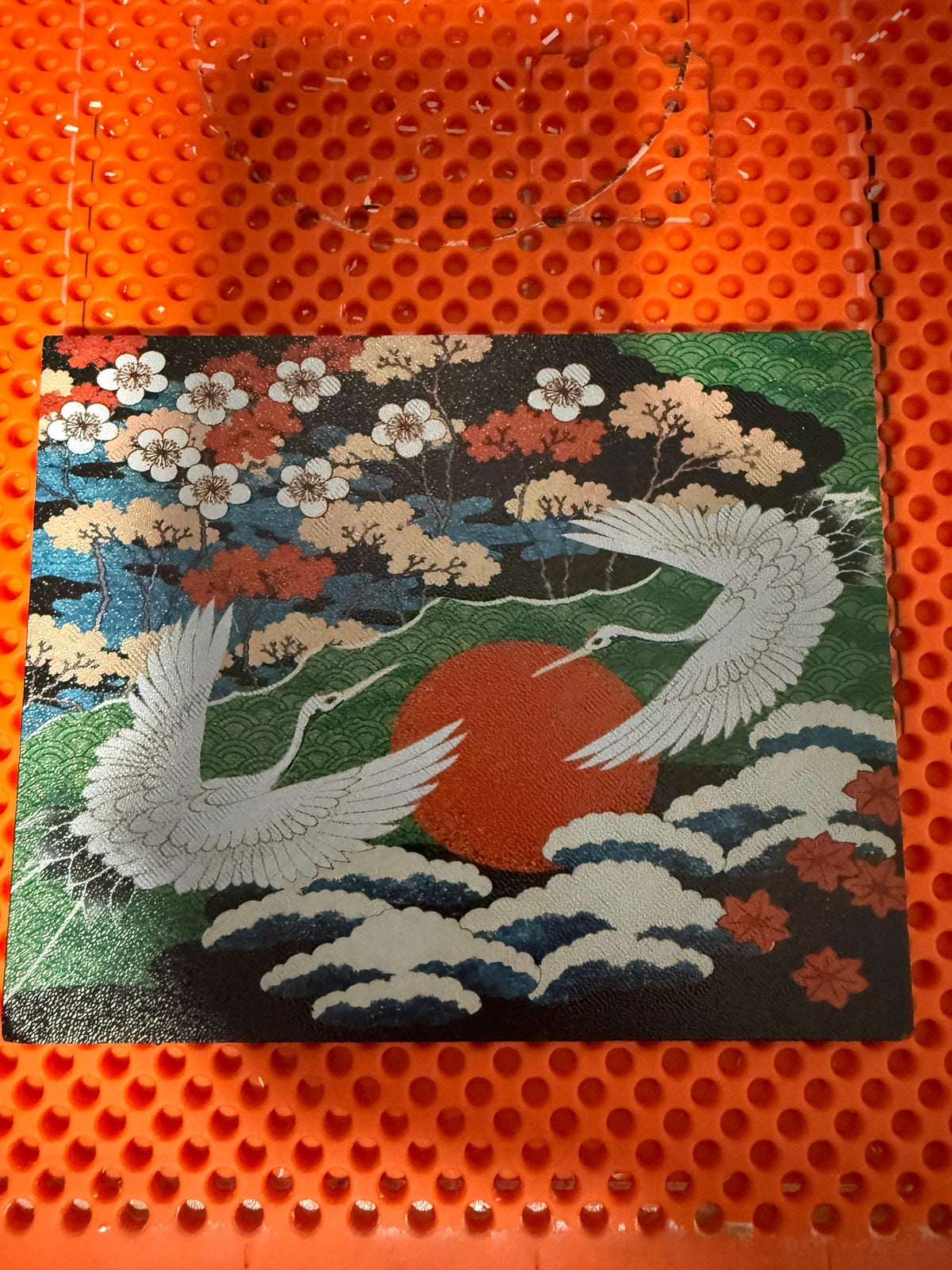 Japanese Crane Steam Machine Faceplate – UV Printed Front Panel | Red Sun & Cherry Blossom Art | Custom Mini PC Cover | Gamer Gift, flat lay of the uninstalled crane faceplate panel with cranes, red sun, and cherry blossoms, on an orange perforated build plate