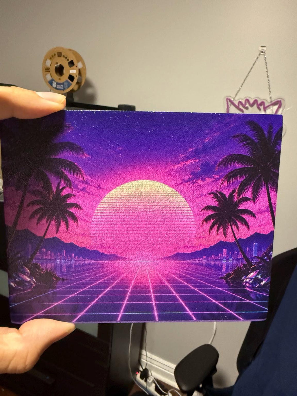 Synthwave Steam Machine Faceplate UV Printed Front Panel | Retro Neon Sunset Grid Art | Custom Mini PC Cover | Gamer Gift, hand holding the uninstalled synthwave faceplate panel, with a 3D printer filament spool in the background