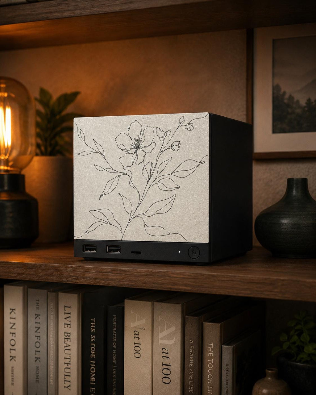 Botanical Line Art Steam Machine Faceplate | Minimalist Plant UV Print Skin with a delicate black line-drawn flower and leaves, shown installed on the console on a wooden bookshelf beside a lit Edison bulb with books below