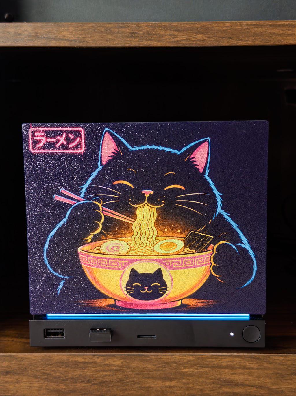 Steam Machine Faceplate Neon Ramen Cat Art | Magnetic UV Printed Panel | Kawaii Japanese Gamer Decor, close-up front view of the Neon Ramen Cat faceplate installed on the console, showing the black cat eating ramen artwork with a glowing blue LED strip