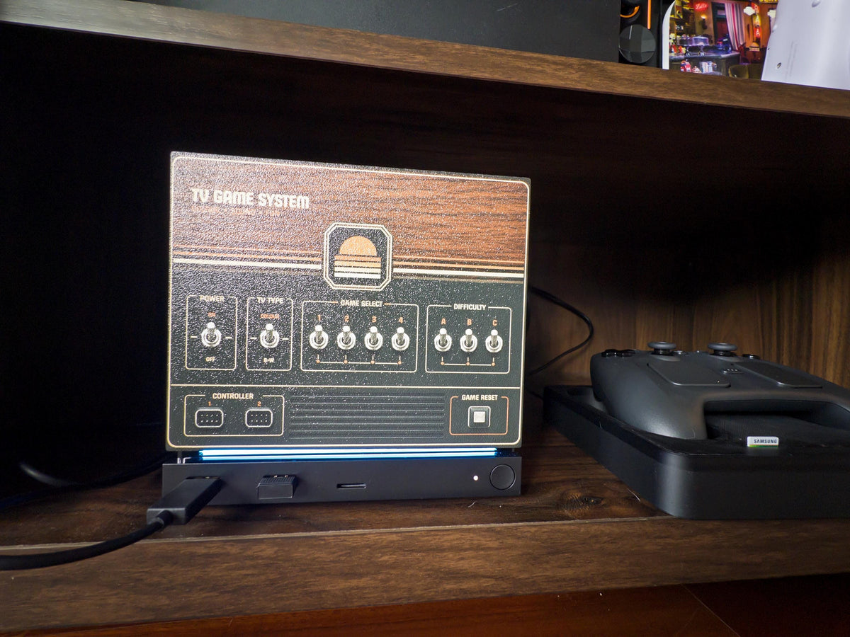 Retro Woodgrain Steam Machine Faceplate – 70s Atari Inspired Console Cover, close-up view of the Steam Machine with the retro woodgrain faceplate installed on a wooden shelf, next to a game controller and its case