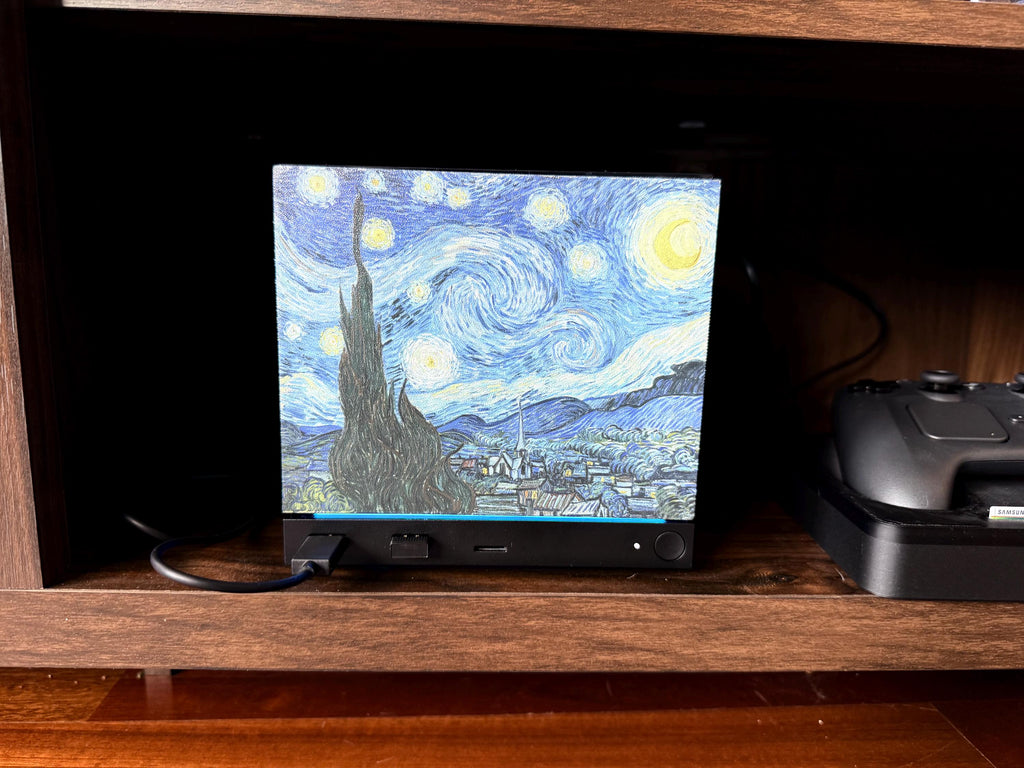 Starry Night Steam Machine Faceplate: Van Gogh Art UV Printed Magnetic Panel, Steam Machine with the Starry Night faceplate installed on a wooden shelf beside a black controller on its charging dock, in dimmer lighting