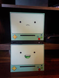 Robot Face Console Skin 2-Pack, Happy Sad Expression, Kawaii Gaming Setup Upgrade, with both skins stacked on a dark wooden shelf, the sad expression plate on top and the happy grinning plate below