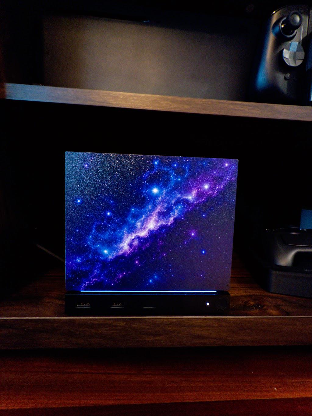 Galaxy Steam Machine Faceplate, UV Printed Nebula Cover, Custom Valve Console Accessory with the purple and blue galaxy nebula artwork, shown installed on the console on a dark wooden shelf with a game controller above