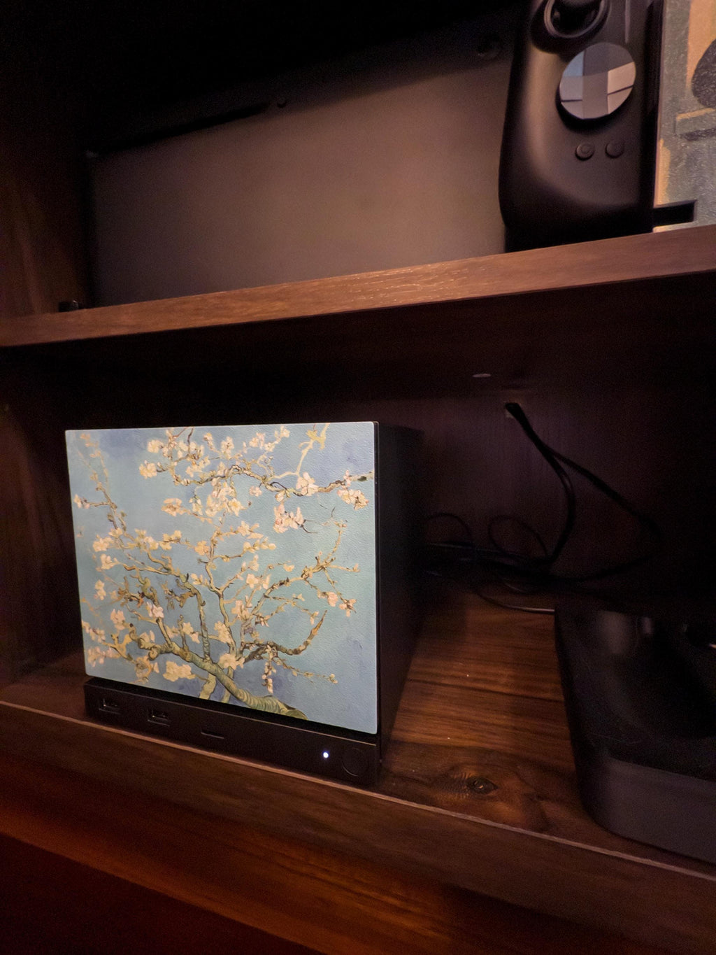 Van Gogh Almond Blossom Steam Machine Faceplate, Magnetic Art Cover Gaming Decor, side-angle view of the Steam Machine with the Almond Blossom faceplate installed on a wooden shelf, with a black game controller on the shelf above