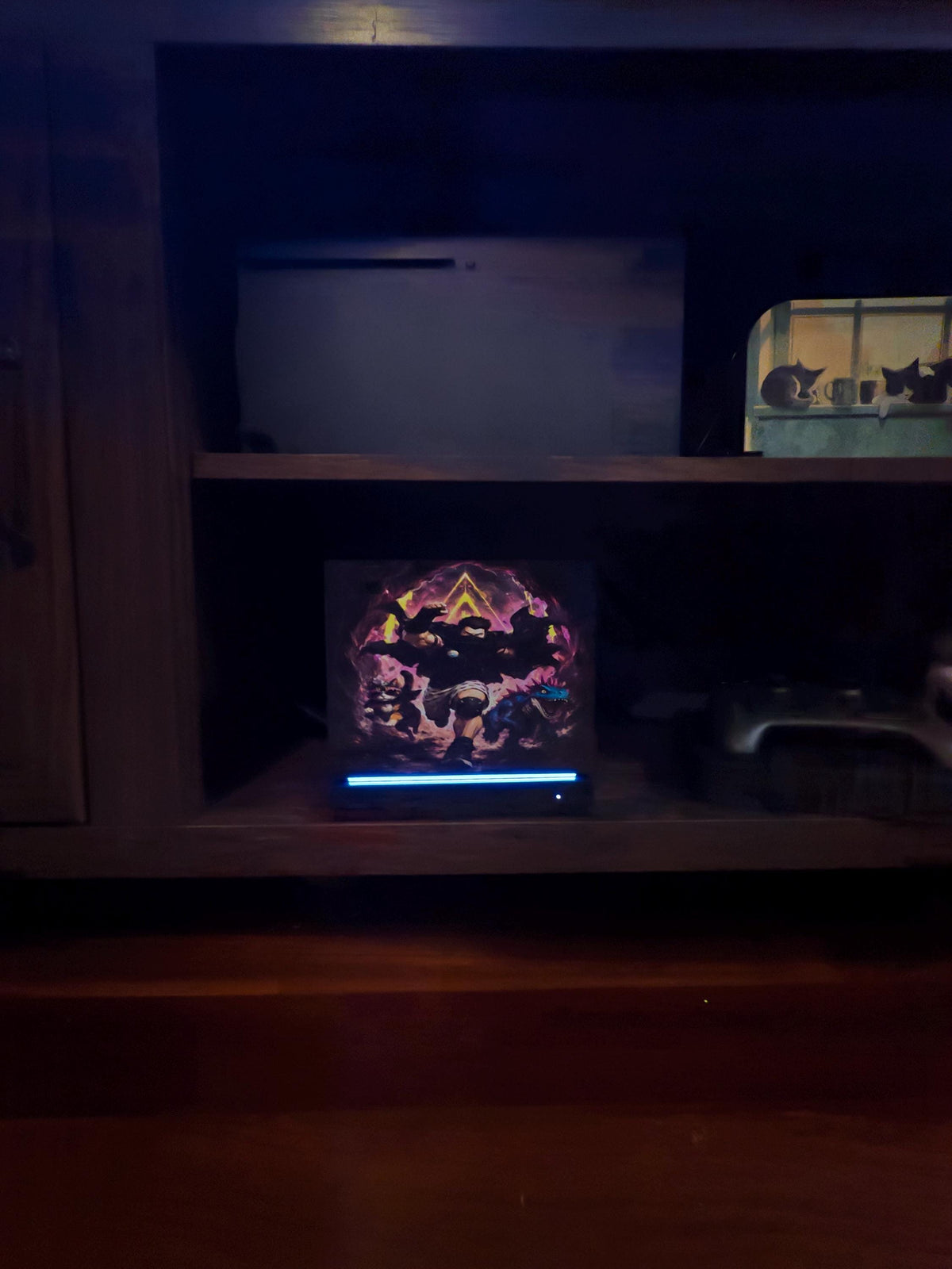Dungeon Crawler Carl Steam Machine Faceplate | Licensed Landfin Studio Art (UV Printed) with the Carl dungeon portal artwork glowing, shown installed on the console inside a dim wooden media cabinet cubby, with the blue LED strip glowing at its base