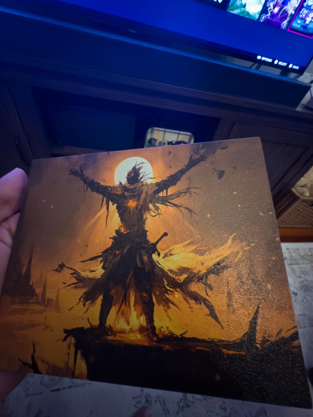 Praise the Sun Steam Machine Faceplate – Dark Fantasy Silhouette (Magnetic UV Print) held in a hand, close-up of the skeletal warrior with outstretched arms against a glowing full moon, with a TV and room background visible