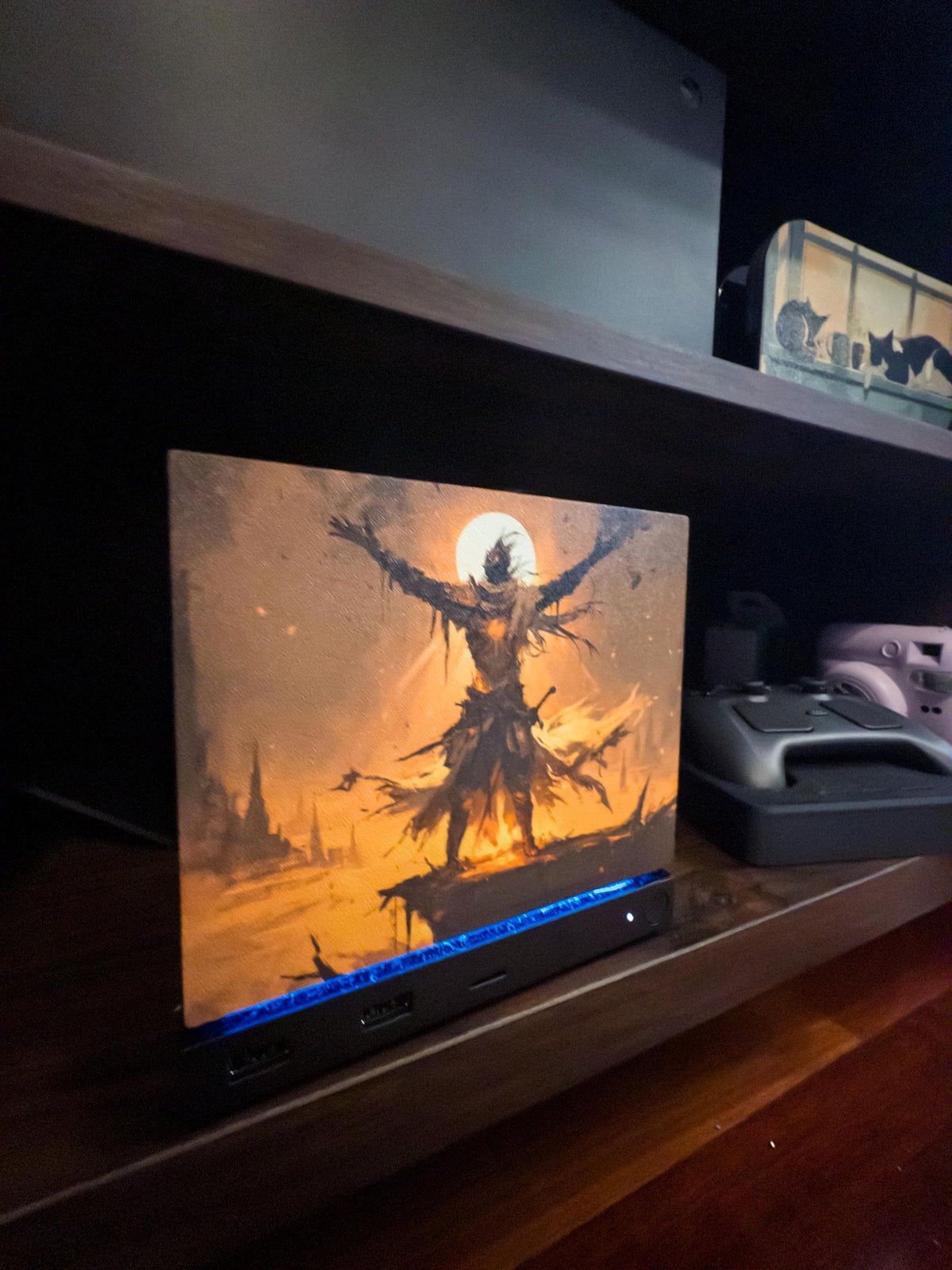 Praise the Sun Steam Machine Faceplate – Dark Fantasy Silhouette (Magnetic UV Print) with a warrior figure with outstretched arms against a glowing moon, shown installed on the console on a wooden shelf next to a game controller