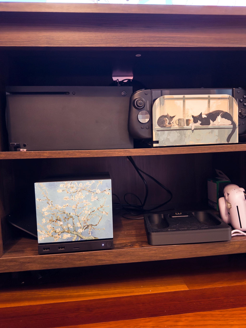 Van Gogh Almond Blossom Steam Machine Faceplate, Magnetic Art Cover Gaming Decor, frontal view of the Steam Machine with the Almond Blossom faceplate installed on the lower shelf of a wooden unit, with an Xbox and a Steam Deck with cat artwork on the shelf above
