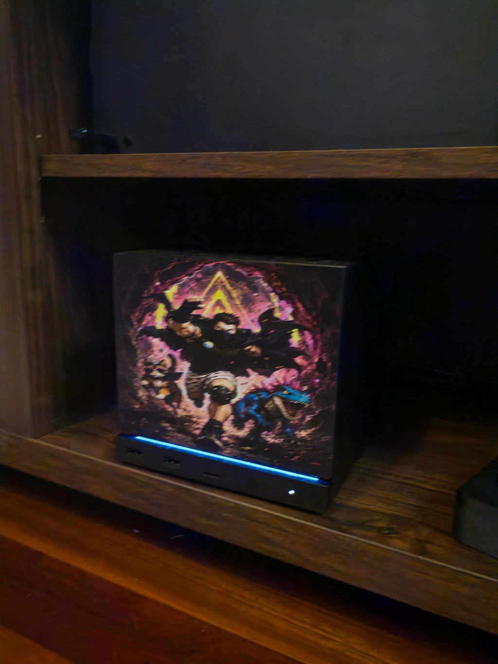 Dungeon Crawler Carl Steam Machine Faceplate | Licensed Landfin Studio Art (UV Printed) with Carl leaping through the glowing dungeon portal, angled close-up installed on the console inside a dark wooden shelf cubby with the blue LED strip glowing at its base