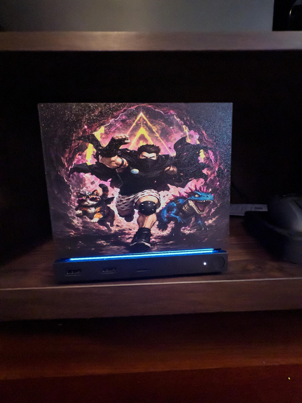 Dungeon Crawler Carl Steam Machine Faceplate | Licensed Landfin Studio Art (UV Printed) with Carl leaping through the glowing dungeon portal, straight-on front view installed on the console on a wooden shelf with the blue LED strip glowing at its base