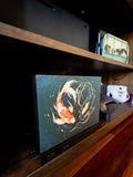 Koi Art Steam Machine Faceplate | Dark Teal Japanese Fish Panel | Magnetic UV Printed Cover | Zen Gamer Gift with two koi circling in dark teal water artwork, angled view installed on the console on a wooden shelf beside a game controller and a white instant camera