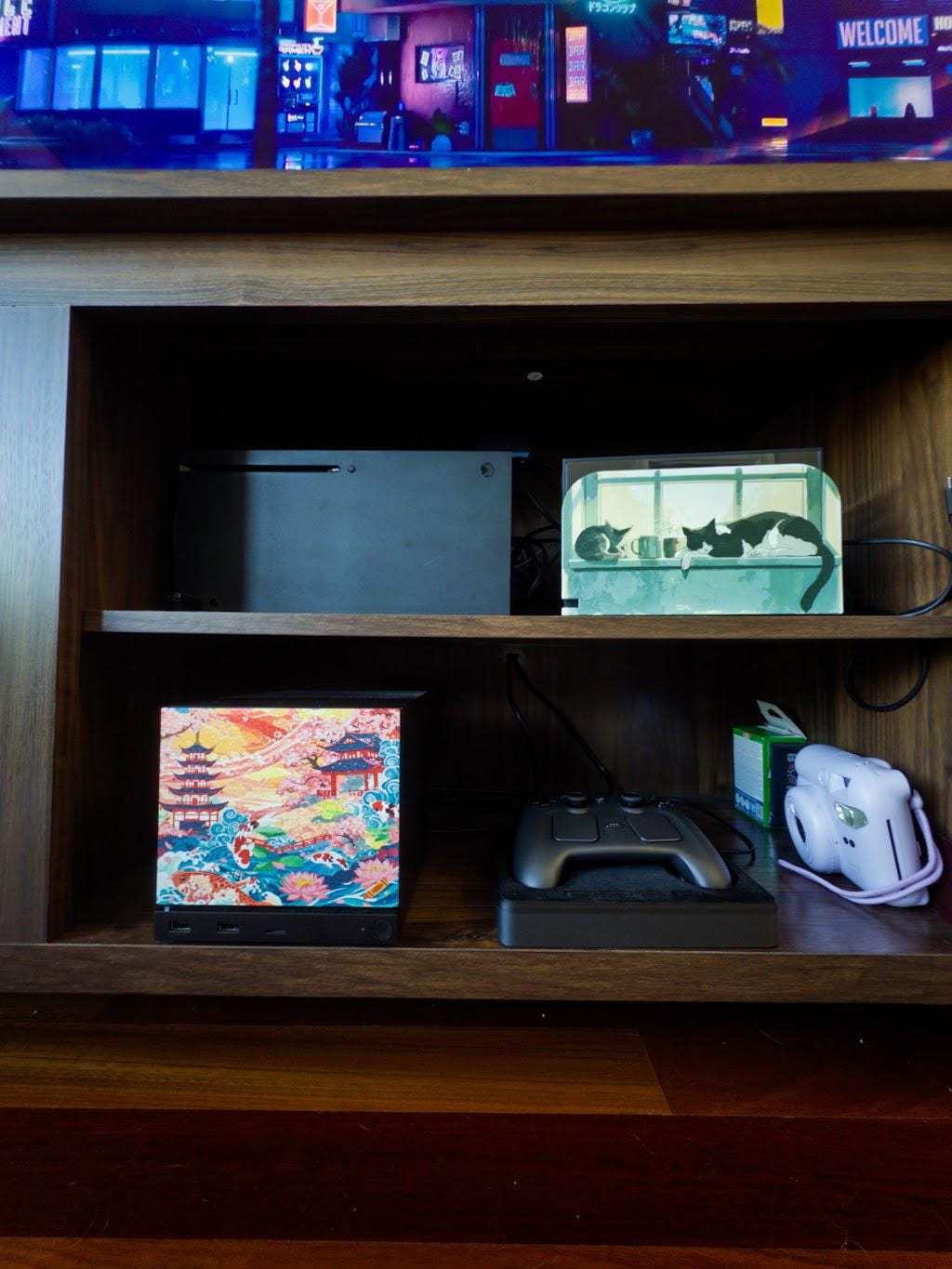 Koi Pagoda Garden Art | Steam Machine Faceplate | Cherry Blossom Sunset Panel | Magnetic UV Printed Cover | Japanese Gamer Gift with the cherry blossom pagoda art, shown installed on the console on a wooden entertainment shelf beside a game controller and a white instant camera