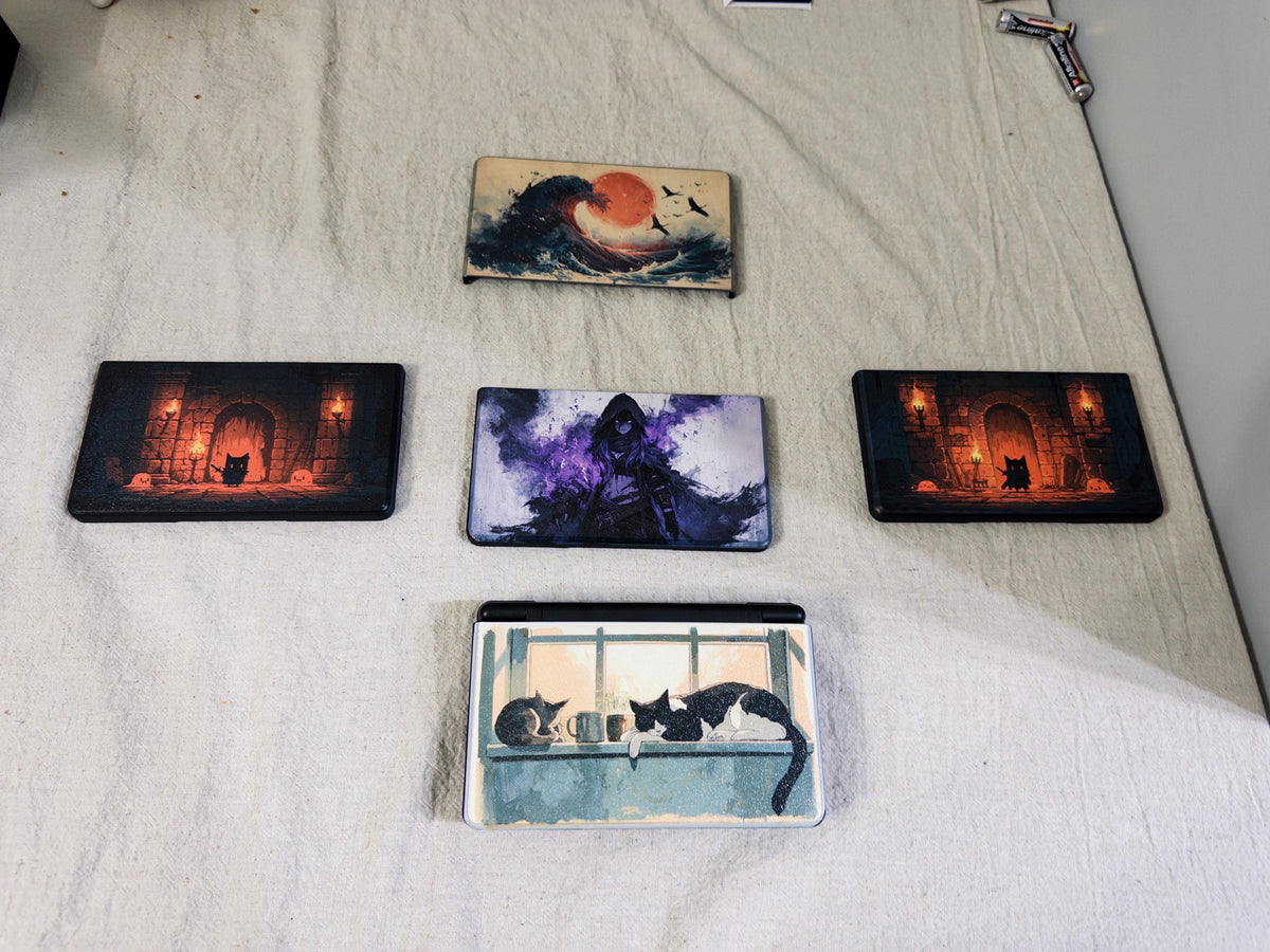 AYN Thor Custom Lid, HD Full Color UV Printed Snap On Cover, Personalized Handheld Faceplate, Your Own Image, Interchangeable Shell, flat lay of five uninstalled printed lids on a light fabric surface showing wave, dungeon door, hooded figure, and window cat designs