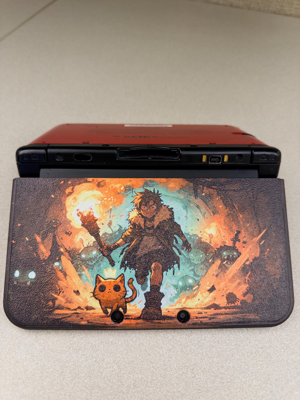 3DS XL Custom Lid, Full Color UV Printed Snap On Cover, Top Shell Faceplate for Original 3DS XL, Your Own Image, Interchangeable Lid, rear view of a red 3DS XL with the uninstalled Torchlight fantasy artwork lid panel shown against the back of the console on a beige floor