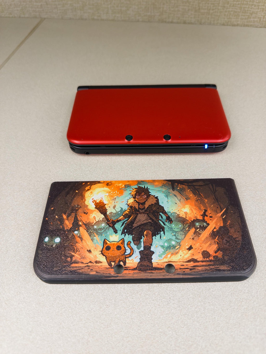 3DS XL Custom Lid, Full Color UV Printed Snap On Cover, Top Shell Faceplate for Original 3DS XL, Your Own Image, Interchangeable Lid, size comparison photo showing the uninstalled Torchlight fantasy artwork lid panel below a closed red 3DS XL console on a light surface