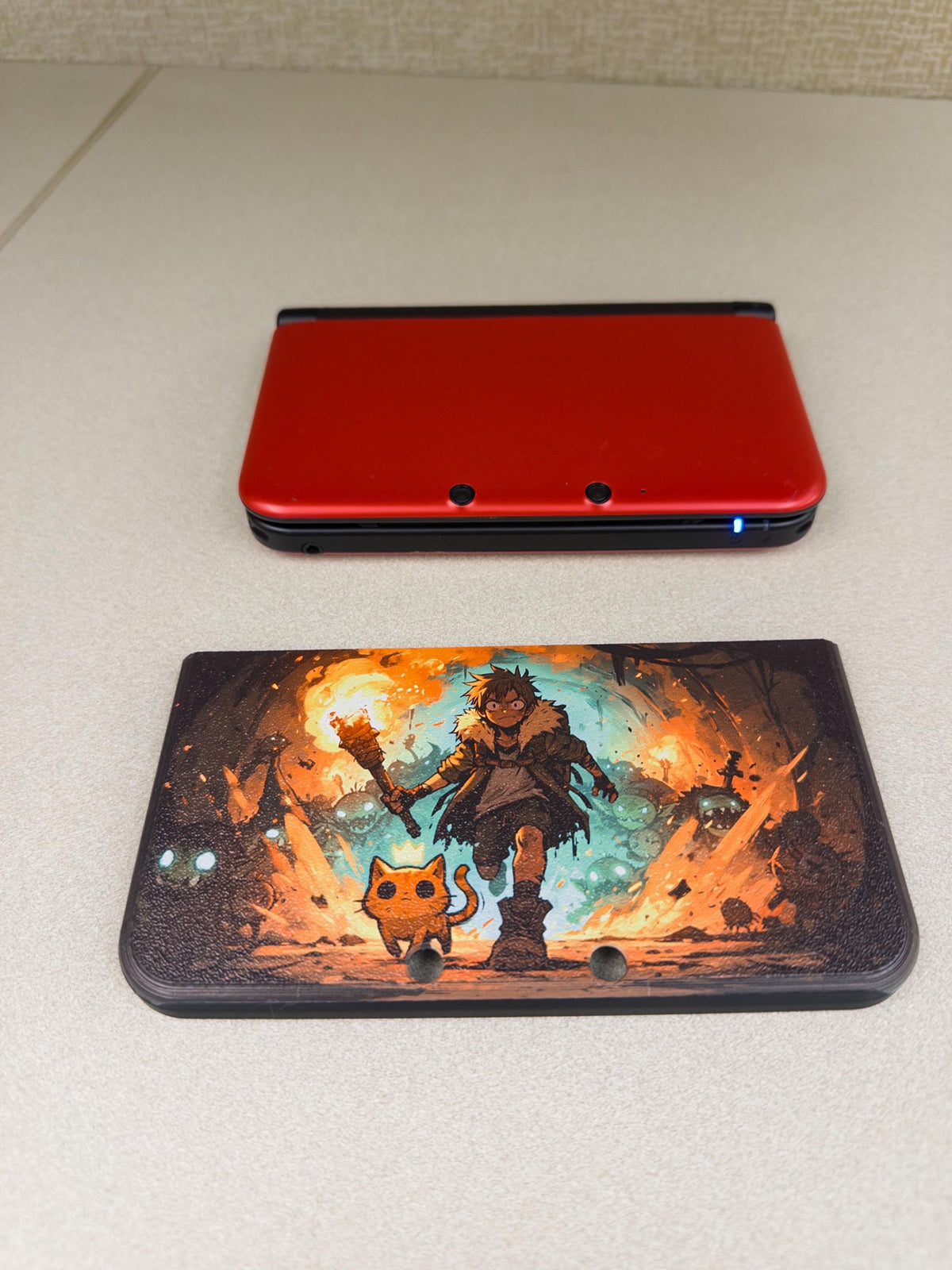 3DS XL Custom Lid, Full Color UV Printed Snap On Cover, Top Shell Faceplate for Original 3DS XL, Your Own Image, Interchangeable Lid, size comparison photo showing the uninstalled Torchlight fantasy artwork lid panel below a closed red 3DS XL console on a light surface
