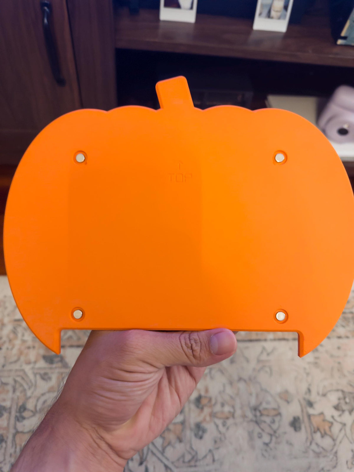 Steam Machine Faceplate Halloween Pumpkin, Classic or Cute Jack o Lantern Magnetic Plate, UV Printed Console Cover, Spooky Gamer Gif, back view of the unprinted orange pumpkin faceplate held in a hand, showing its four magnets and embossed TOP label