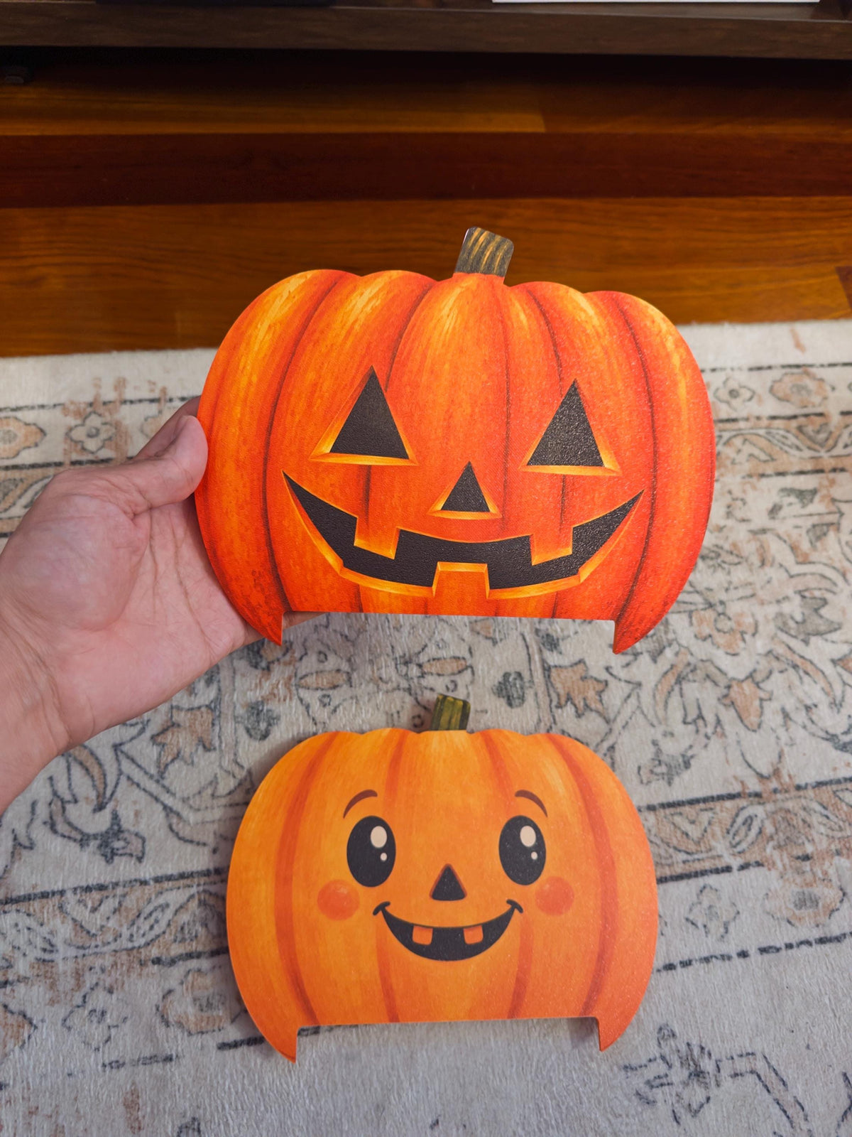 Steam Machine Faceplate Halloween Pumpkin, Classic or Cute Jack o Lantern Magnetic Plate, UV Printed Console Cover, Spooky Gamer Gif, hand holding the uninstalled classic carved jack-o-lantern pumpkin faceplate, with the cute pumpkin faceplate on a patterned rug below