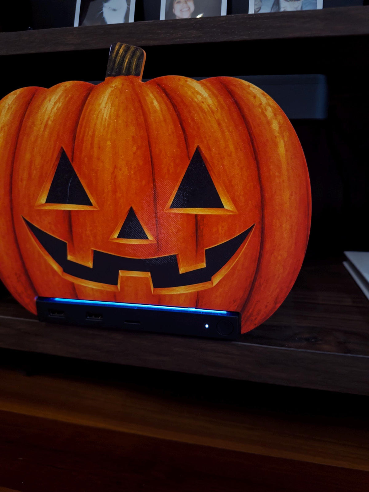 Steam Machine Faceplate Halloween Pumpkin, Classic or Cute Jack o Lantern Magnetic Plate, UV Printed Console Cover, Spooky Gamer Gif, close-up front view of the classic carved jack-o-lantern pumpkin faceplate installed on the Steam Machine on a dark wooden shelf, with the console's blue light strip glowing below