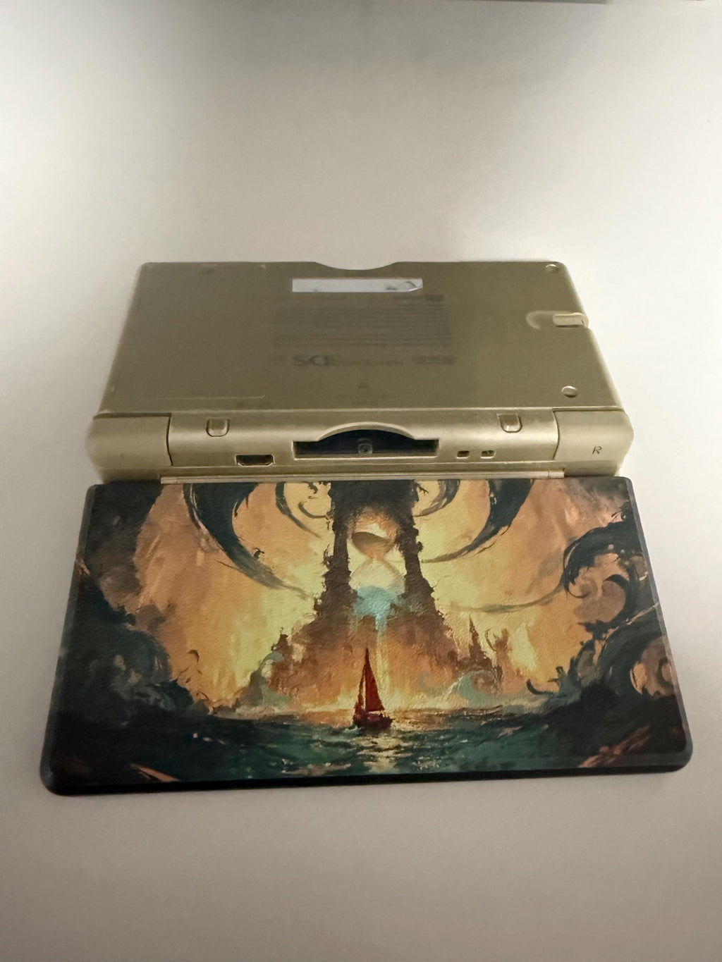 DS Lite Custom Lid, Full Color UV Printed Snap On Cover, Top Shell Faceplate for Original DS Lite, Your Own Image, Interchangeable Lid, DS Lite with the fantasy sea and glowing tower artwork lid installed, resting on a matching printed desk mat with the same artwork