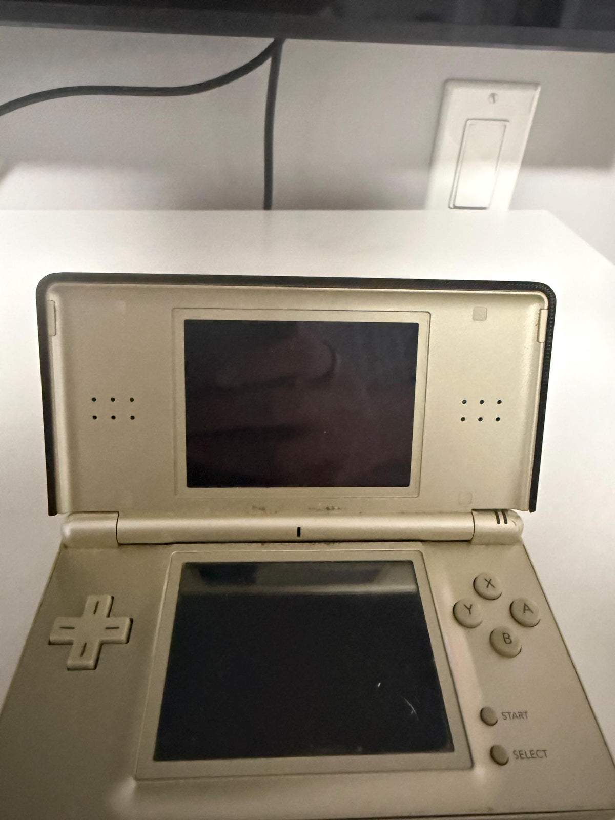 DS Lite Custom Lid, Full Color UV Printed Snap On Cover, Top Shell Faceplate for Original DS Lite, Your Own Image, Interchangeable Lid, open silver DS Lite console with its screens off shown from the front on a white surface, with a wall light switch and a black cord in the background