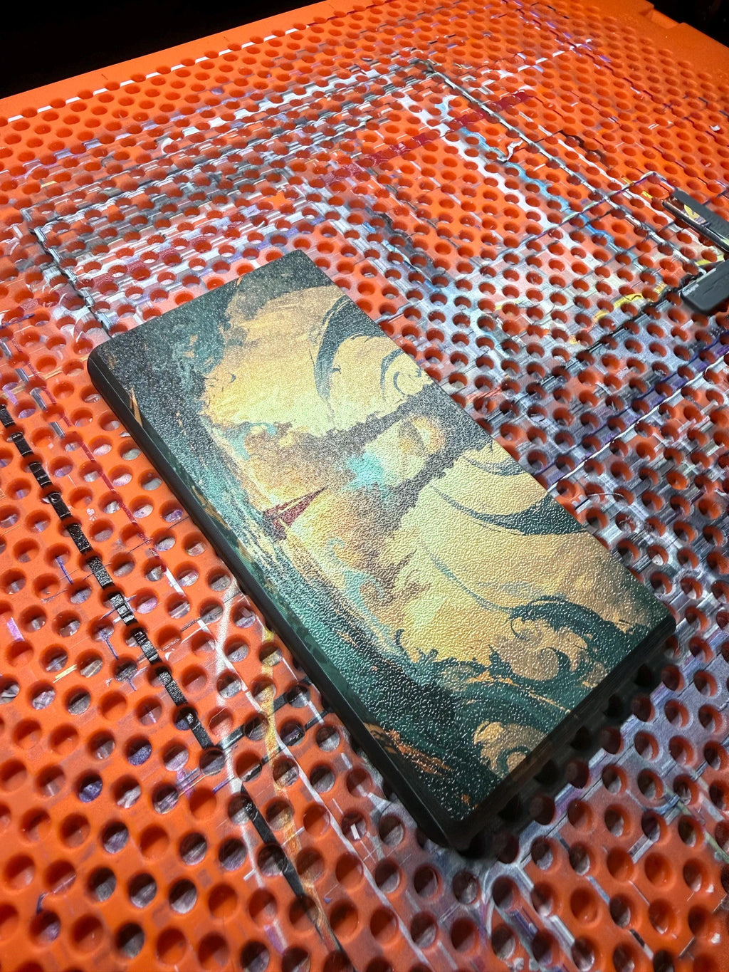 DS Lite Custom Lid, Full Color UV Printed Snap On Cover, Top Shell Faceplate for Original DS Lite, Your Own Image, Interchangeable Lid, close-up of the uninstalled lid panel printed with a green and gold marbled artwork, lying on an orange perforated build plate