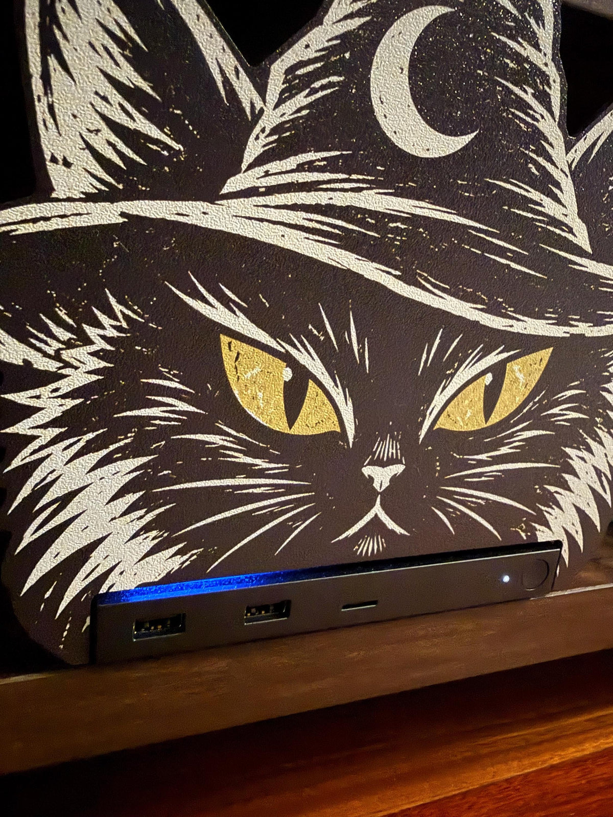Steam Machine Faceplate Black Cat Witch Hat, Halloween Witchy Cat Magnetic Plate, UV Printed Console Cover, Spooky Gamer Gift, close-up of the black cat witch hat faceplate installed on the Steam Machine, showing its yellow eyes and crescent moon witch hat on a wooden surface