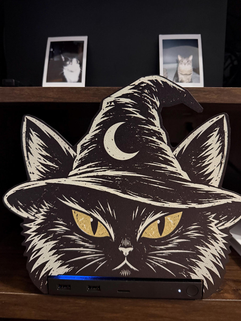Steam Machine Faceplate Black Cat Witch Hat, Halloween Witchy Cat Magnetic Plate, UV Printed Console Cover, Spooky Gamer Gift, close-up of the black cat witch hat faceplate installed on the Steam Machine, showing the console's front ports and blue light strip, with two instant cat photo prints on the shelf above