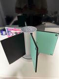 Steam Machine Faceplate Organizer, Spinning 3D Printed Display Stand, Rotating Plate Holder, Gamer Desk Setup, Gift for Gamer, Holds 6, eye-level view of the organizer with its six arms fanned out holding faceplates, showing the blank mint green back of one plate, on a white desk with a blurred monitor behind