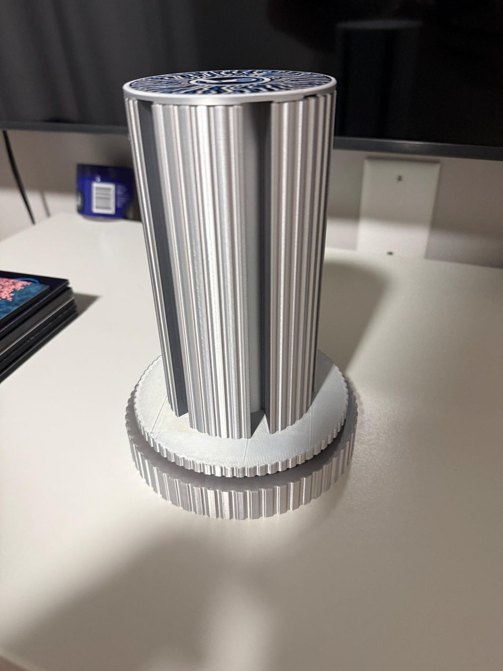Steam Machine Faceplate Organizer, Spinning 3D Printed Display Stand, Rotating Plate Holder, Gamer Desk Setup, Gift for Gamer, Holds 6, empty silk silver organizer column standing alone on a white desk with a dark monitor behind, with a stack of faceplates beside it, showing the circuit-board patterned top cap