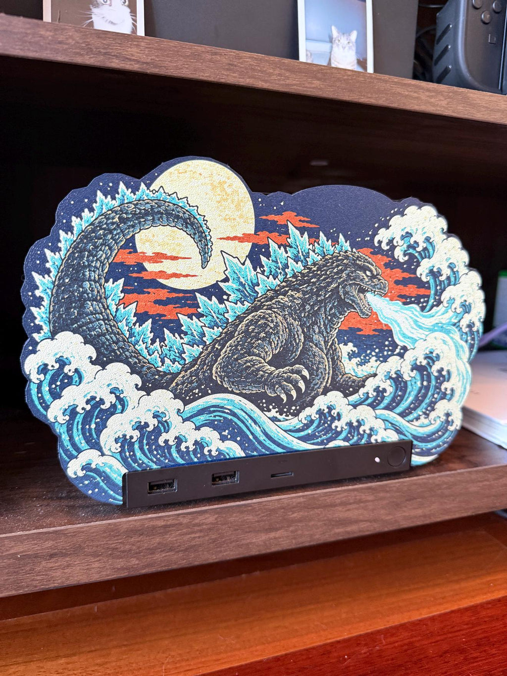 Steam Machine Faceplate, Custom Faceplate, Godzilla Kaiju Plate XL Oversized, Magnetic Console Cover, Monster Gamer Gift, Japan Wave Decor, front view of the Godzilla kaiju XL faceplate installed on the console on a dark wooden shelf, with cat photo prints visible on the shelf above