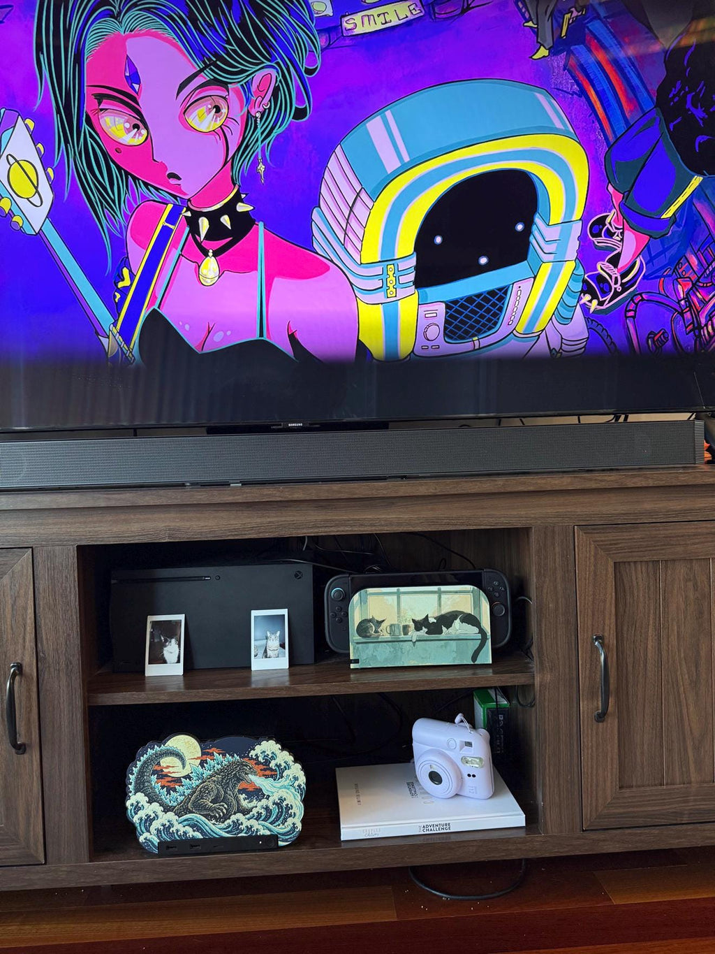 Steam Machine Faceplate, Custom Faceplate, Godzilla Kaiju Plate XL Oversized, Magnetic Console Cover, Monster Gamer Gift, Japan Wave Decor, Godzilla kaiju XL faceplate installed on the open shelf of a wooden media console below a television showing an anime-style illustration, beside a white book with a lavender instant camera
