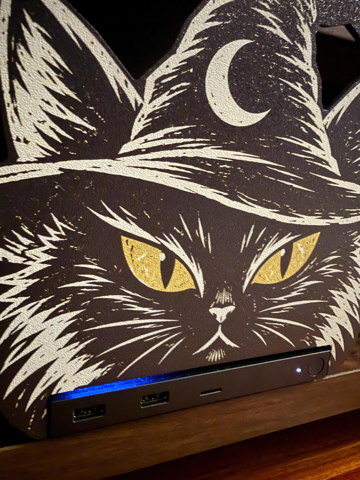 Steam Machine Faceplate Black Cat Witch Hat, Halloween Witchy Cat Magnetic Plate, UV Printed Console Cover, Spooky Gamer Gift, extreme close-up of the black cat witch hat faceplate installed on the Steam Machine, showing the gold glittery eyes and crescent moon on the witch hat with the console's blue light strip below