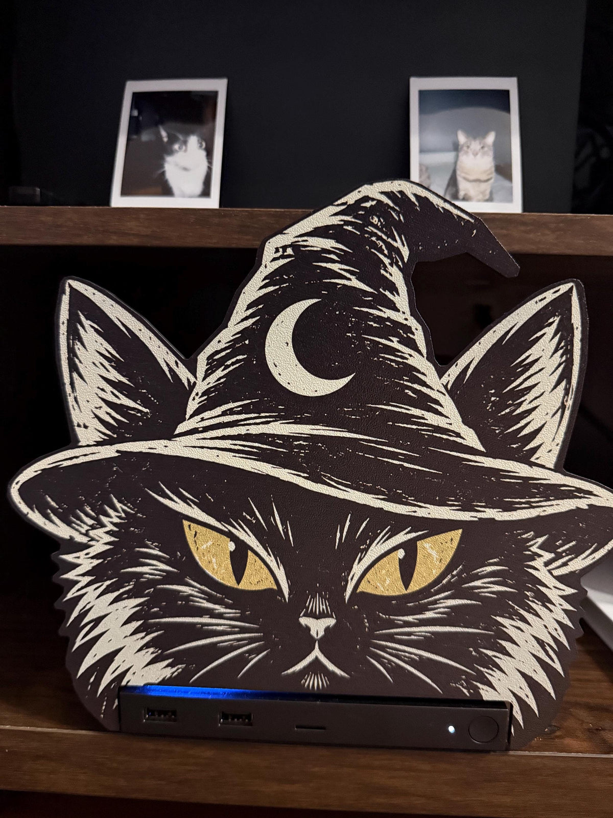 Steam Machine Faceplate Black Cat Witch Hat, Halloween Witchy Cat Magnetic Plate, UV Printed Console Cover, Spooky Gamer Gift, close-up front view of the black cat witch hat faceplate installed on the Steam Machine, showing the console's USB ports and blue light strip, with two instant cat photo prints on the shelf above