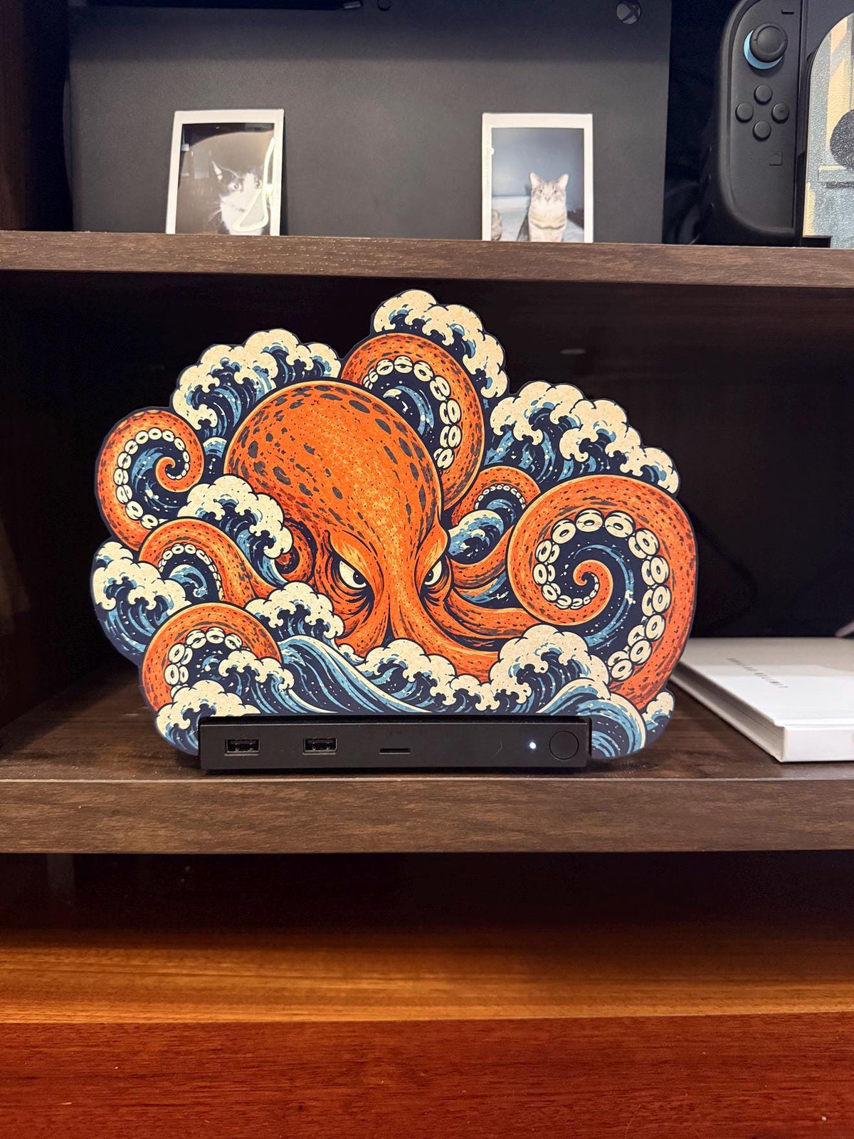 Steam Machine Faceplate, Custom Faceplate, Kraken Kaiju Plate XL Oversized, Magnetic Console Cover, Octopus Gamer Gift, Japan Wave Decor, front view of the Kraken kaiju XL faceplate with an orange octopus rising out of Japanese waves, installed on the console on a wooden shelf beside a white book