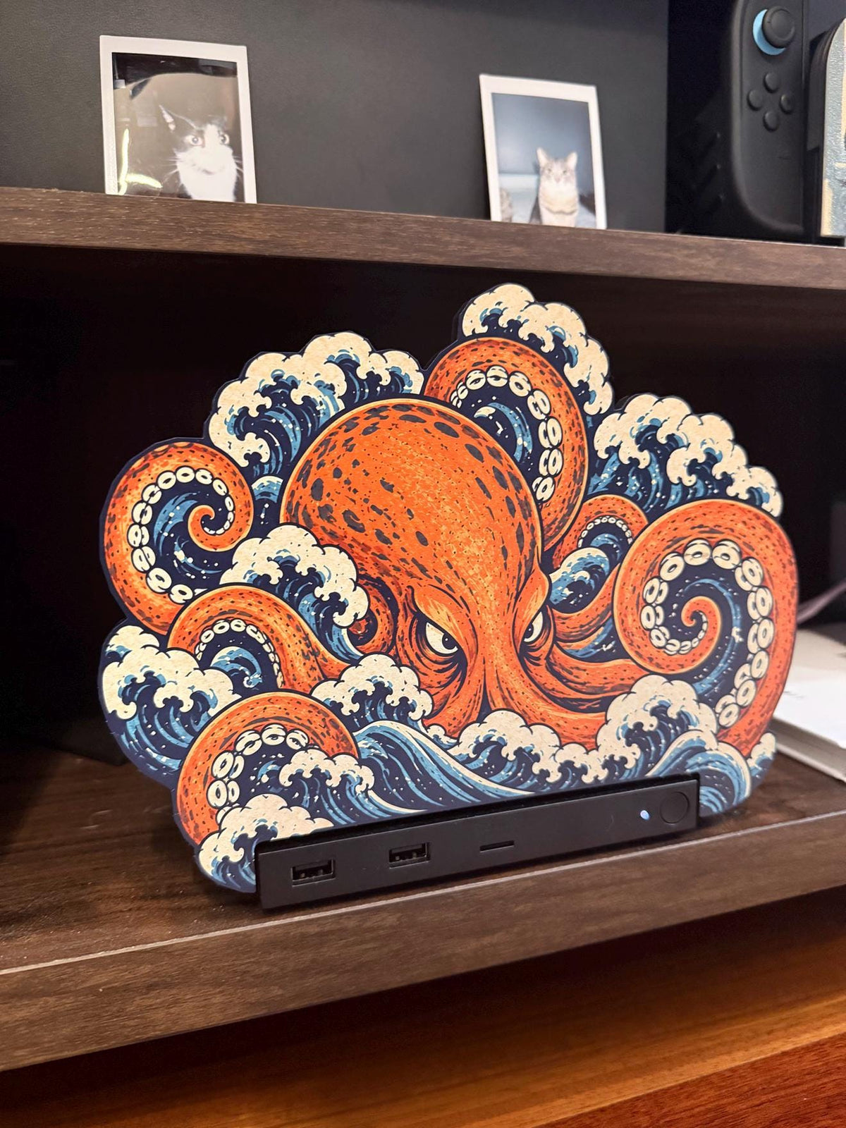 Steam Machine Faceplate, Custom Faceplate, Kraken Kaiju Plate XL Oversized, Magnetic Console Cover, Octopus Gamer Gift, Japan Wave Decor, close-up front view of the Kraken kaiju XL faceplate with an orange octopus amid blue and white Japanese waves, installed on the console on a wooden shelf with two framed cat photos above